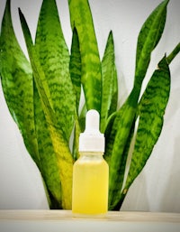 a bottle of aloe vera in front of a plant